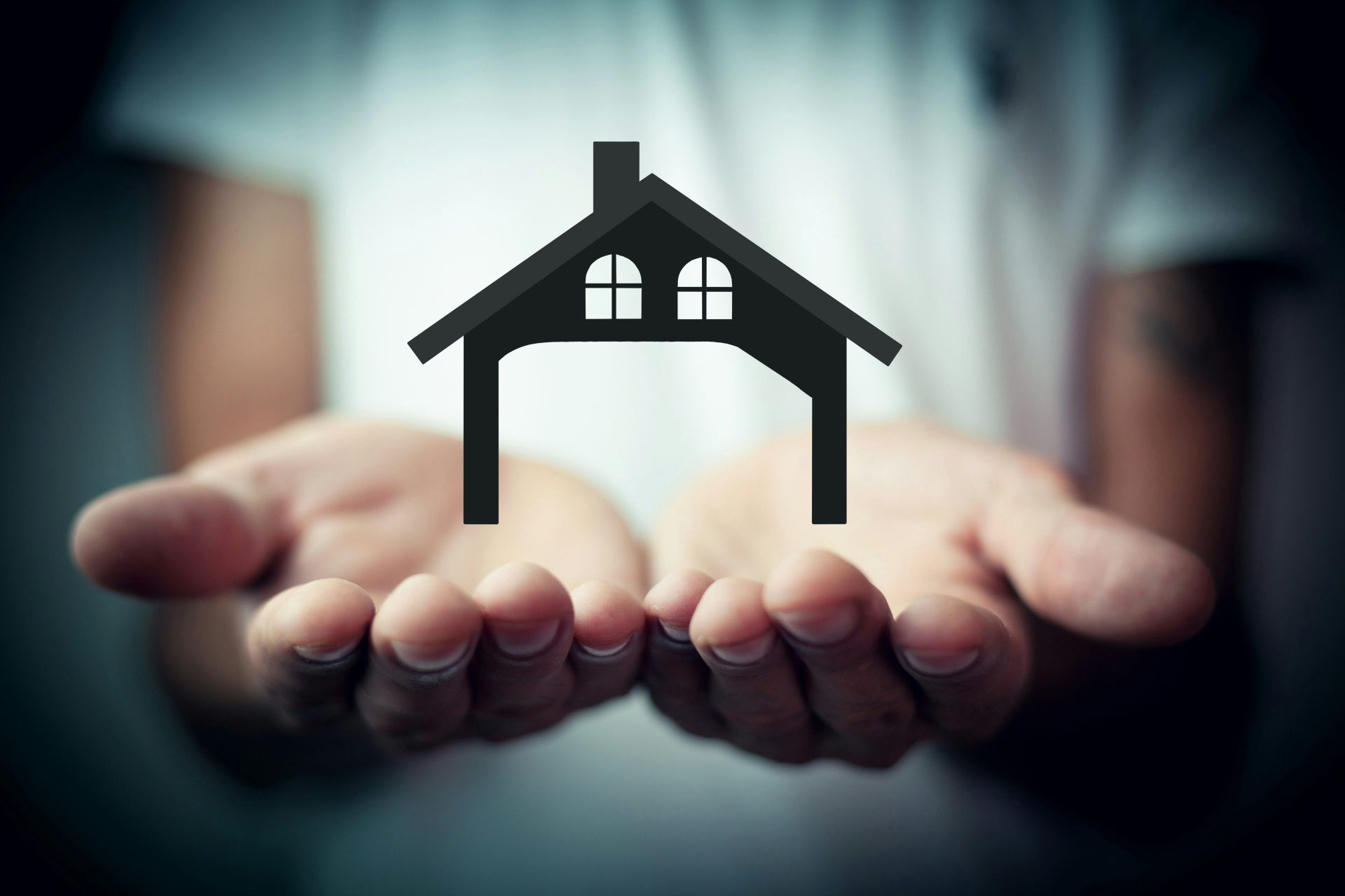 Hände, die die Silhouette eines Hauses halten